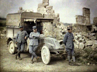 Three French soldiers parked in front of a heavily damaged building with a small truck, Aisne, France
